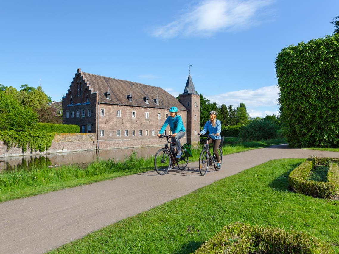 Blick auf Schloss Gracht mit Radfahrern im Park